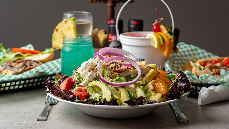 Summer time salad with bucket cocktail and other entrees in background